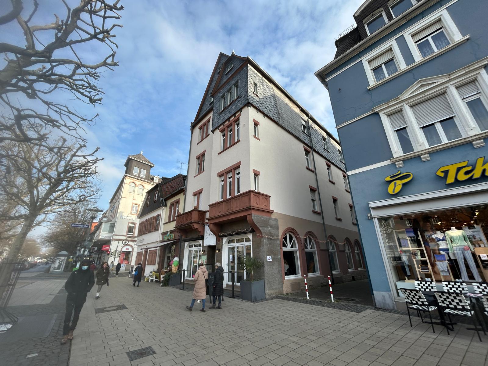 Städtische Szenerie mit historischen Gebäuden und Geschäften an einer belebten Straße.